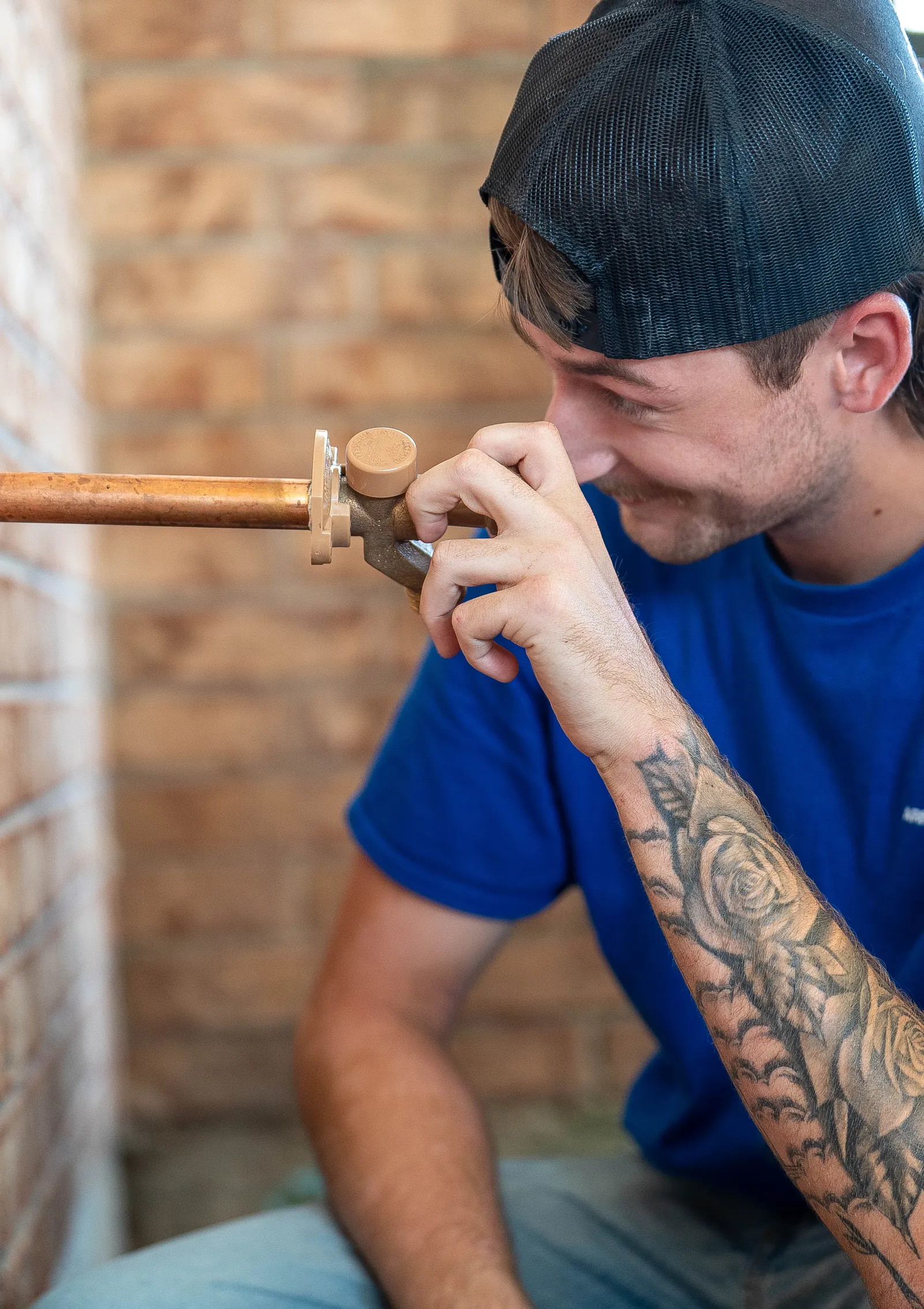 Arnold's team member working on an outdoor faucet beside a brick wall